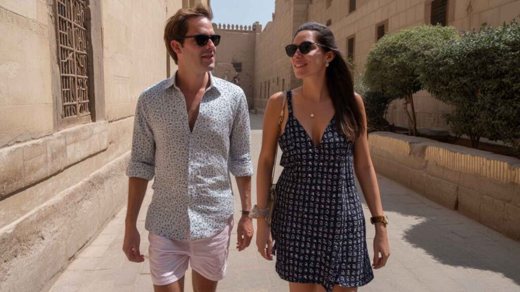 Young man and woman in Cairo during April, dressed for warm weather with light clothing and sunglasses, walking by a market